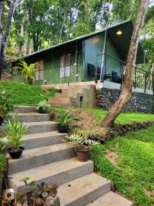 uma casa verde com escadas em frente em Trickling Stream Campsite em Alawala