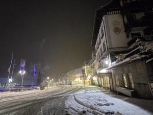 a snow covered street at night with a building at Miuti Residence in Triberg