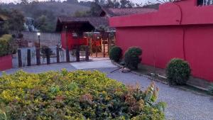 a pink house with a fence and some bushes at Chacara recanto mineiro in Jarinu
