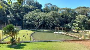 a pond in a park with a fence and trees at Chacara recanto mineiro in Jarinu