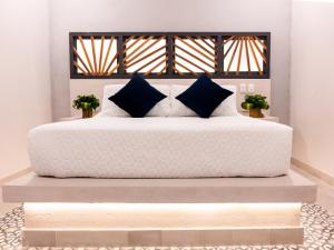 a large white bed with blue pillows on it at The Garden Suites in Santa Marta