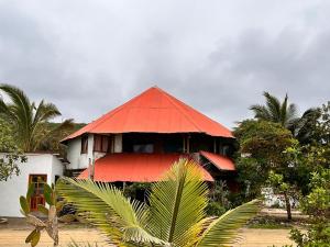 a building with a red roof in front of trees at Wipeout Cabaña Restaurant in Las Tunas