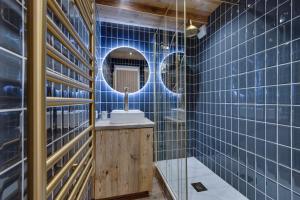 Un baño con azulejos azules, lavabo y espejo. en Au 6ème ciel Tignes 2100m - Vue Lac & Montagnes - Proche pistes - 2 adultes et 2 enfants, en Tignes 54 fotos más