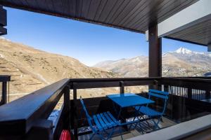 una mesa y sillas en un balcón con montañas en Au 6ème ciel Tignes 2100m - Vue Lac & Montagnes - Proche pistes - 2 adultes et 2 enfants, en Tignes