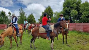 a group of people riding horses in a field at Balcon al Cotopaxi Hosteria in Sangolquí
