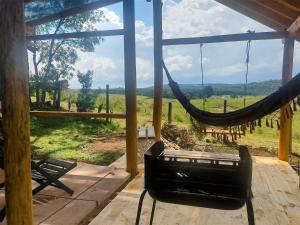 a hammock on a porch with a view of a field at Na'raucária in Cambará