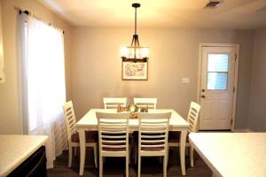 a dining room table with white chairs and a chandelier at 5 Min To Navarre Beach Patio Cute Design Kitchen in Navarre