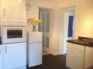 una cucina con armadi bianchi e un vaso di fiori di Hazeldene Apartment Unit a Perth