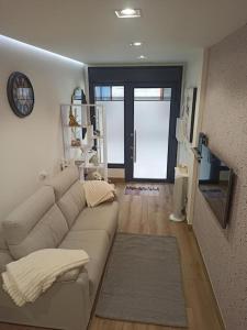 a living room with a couch and a clock on the wall at La Casita de Vane - Casa en el centro con parking privado a unos 250 metros in Cangas de Morrazo