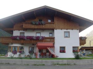 a large white building with wooden balconies and flowers at Appartementhaus Honznhof in Längenfeld