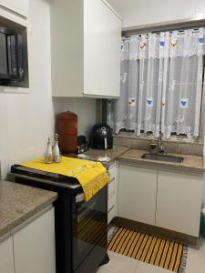 a kitchen with white cabinets and a sink at Quarto em apartamento in Ouro Preto +5 photos