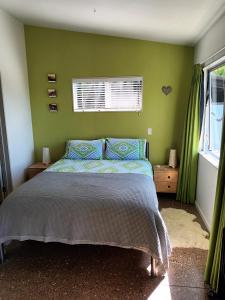 Un dormitorio con una cama y una pared verde. en Island Breeze, en Oneroa