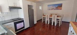 a kitchen with a table with chairs and a refrigerator at Edladleni Guesthouse Quigney in East London