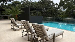 three chairs sitting next to a swimming pool at Luxury apartment 10 min to Airport Be Cariari Condo #402 in La Asunción