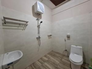 a bathroom with a white toilet and a sink at Pondok Roomi Villa in Sembalun Lawang