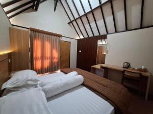 a bedroom with two beds and a desk and a window at Pondok Roomi Villa in Sembalun Lawang