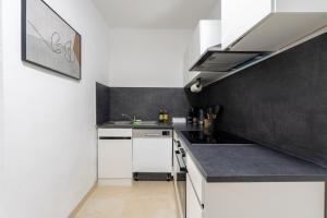 una cucina con armadietti bianchi e una parete nera di Modern 55m2 Apartment Near Vienna - Ideal for Work, Leisure and Relaxation in Nature a Kaltenleutgeben