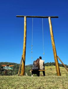 a man and a woman sitting on a swing at Pousada Verdes Alpes in Santo Antônio do Pinhal