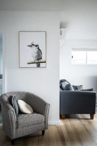 a living room with a bird sitting on a chair at Orion Beach Cottage B - Jervis Bay in Vincentia