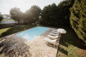 a swimming pool with a group of lounge chairs next to it at NaNa House Ericeira - Yoga & Surf in Santo Isidoro