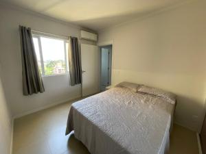 ein Schlafzimmer mit einem weißen Bett und einem Fenster in der Unterkunft Apto Home Club 500m Praia Piçarras 20 min Beto Carrero - ANG905C in Piçarras + 54 Fotos