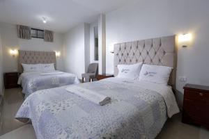 a hotel room with two beds with white sheets at Witobi Hostal in Cajamarca