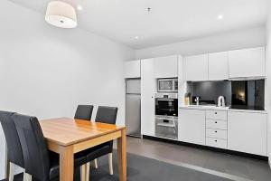 a kitchen with a wooden table and black chairs at Gibson Mill waterfront warehouse apartment - 204 in Hobart