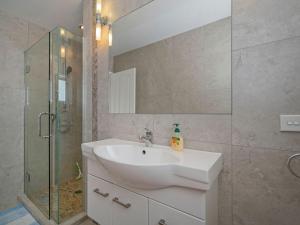a bathroom with a sink and a glass shower at Hosts on the Coast Beach on Buffalo in Whitianga +26 photos