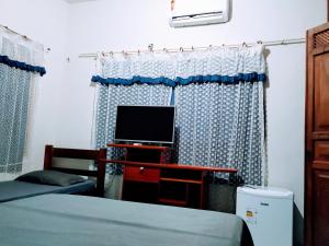 a bedroom with a bed and a tv and a desk at Pousada 4 cantos in Corumbá