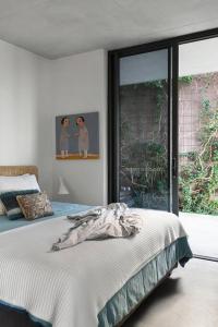 Un dormitorio blanco con una cama y una ventana. en Eyrie House by Noosa Secret Destinations, en Sunrise Beach