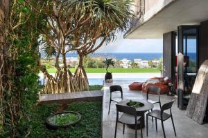 un patio con sillas y una mesa con vistas al océano en Eyrie House by Noosa Secret Destinations, en Sunrise Beach