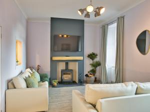Una sala de estar con dos sofás blancos y una chimenea. en Elfin Cottage - Uk7810, en Coirantee