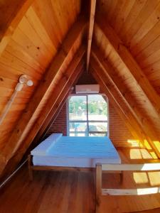 un letto in mansarda con finestra di Cabaña Coralina a Bialet Massé