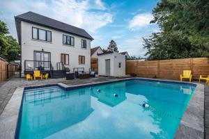 a swimming pool in front of a house at Modern Home Pool Still Open Two Fire Pits Free Parking Game Room in Toronto
