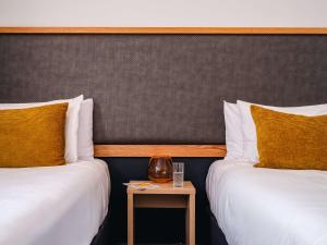 two beds in a hotel room with a side table at WQ Wellington Quarter Hotel in Wellington
