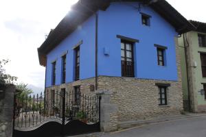 a blue house with a fence on a street at La Ería de Colombres in Colombres