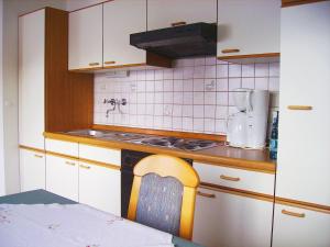 a kitchen with white cabinets and a stove and a chair at Ferienwohnung Kappauf / Petrik in Friedenfels