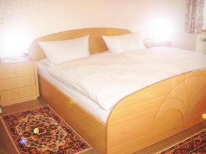 Schlafzimmer mit einem Holzbett mit weißer Bettwäsche und einem Teppich in der Unterkunft Ferienwohnung Kappauf / Petrik in Friedenfels