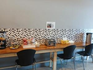 浦项Pohang Cheongha Call Self Check-in Motel的一个带三把椅子的柜台和一张带收音机的桌子