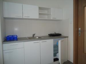 una cocina con armarios blancos y fregadero en Apartments Valentka, en Bešeňová