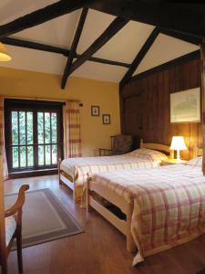 a bedroom with two beds and a large window at Combe Lancey Farmhouse B&B in Crediton