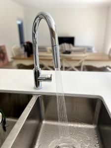 a kitchen sink with water pouring from a faucet at The Cosy Cottage in Ararat