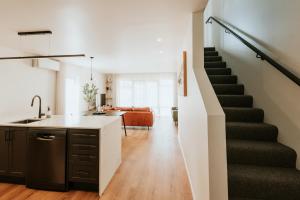 a kitchen and a living room with a staircase at The Kings Domain, DUKE - Luxurious townhouse in the CBD! in Blenheim