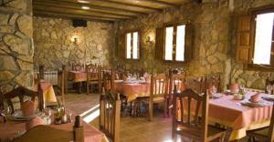 a restaurant with tables and chairs and a stone wall at Hostal Restaurante Sierra De La Martina in Charilla +56 photos