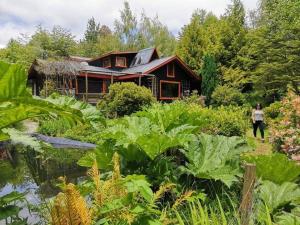 Eine Frau steht vor einem Haus mit Garten in der Unterkunft Pucón Magic forest in Pucón