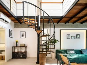 a spiral staircase in a living room with a green couch at Berawa Lofts #2 Canggu in Canggu