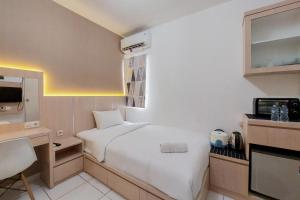 a hotel room with a bed and a television at Cozy and Minimalist Studio (No Kitchen) at Aeropolis Apartment By Travelio in Tangerang