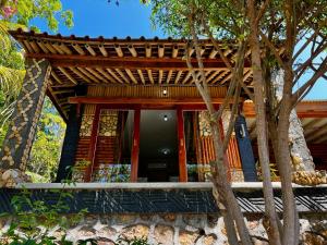 a house with a wooden roof and a tree at Are Guling Beach Bungalows in Kuta Lombok