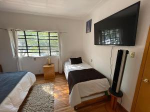 a bedroom with two beds and a flat screen tv at Hostal Roma Condesa in Mexico City