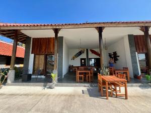 a patio with wooden tables and chairs in a house at Are Guling Beach Bungalows in Kuta Lombok